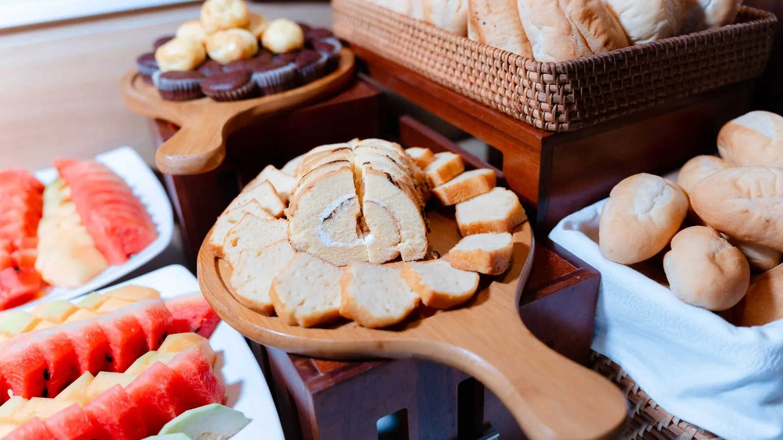 Breakfast buffet with baskets of bread, sliced loaves, pastries and platters of fresh fruit