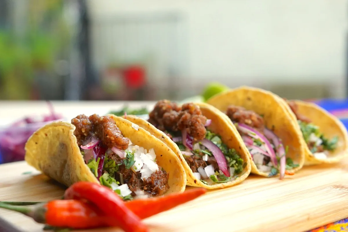 Beef tacos in corn tortillas topped with onions and cilantro