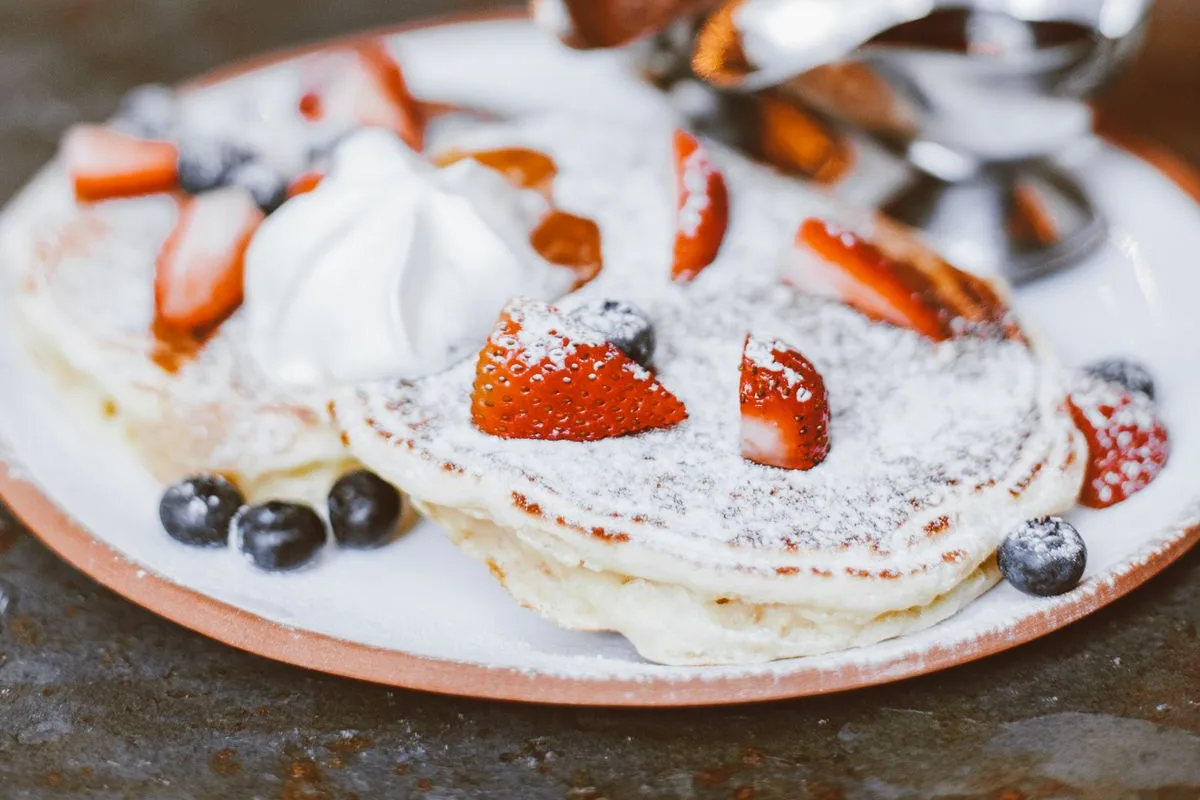 Pancakes topped with strawberries, blueberries, whipped cream and powdered sugar