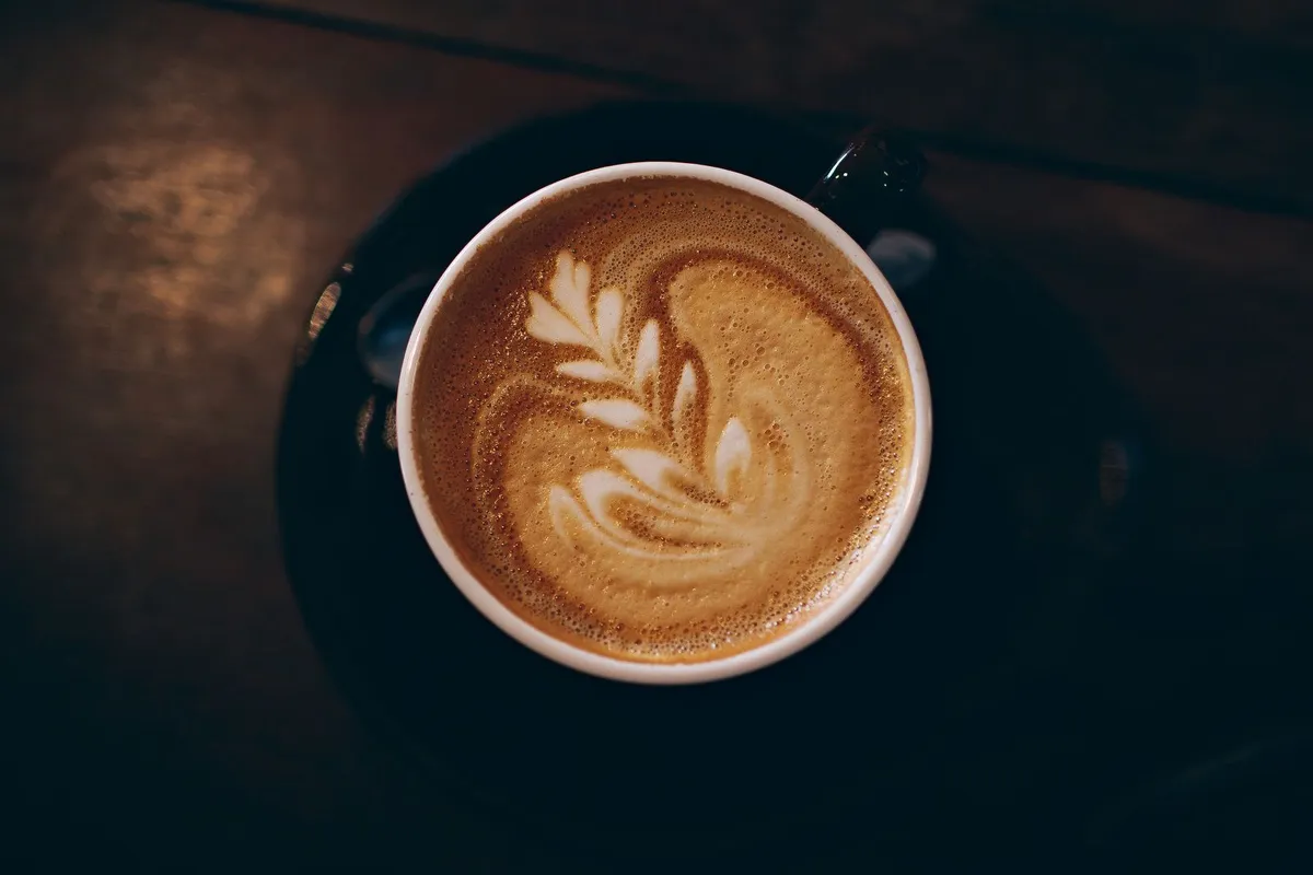 Cup of coffee with leaf-shaped latte art on a wooden table
