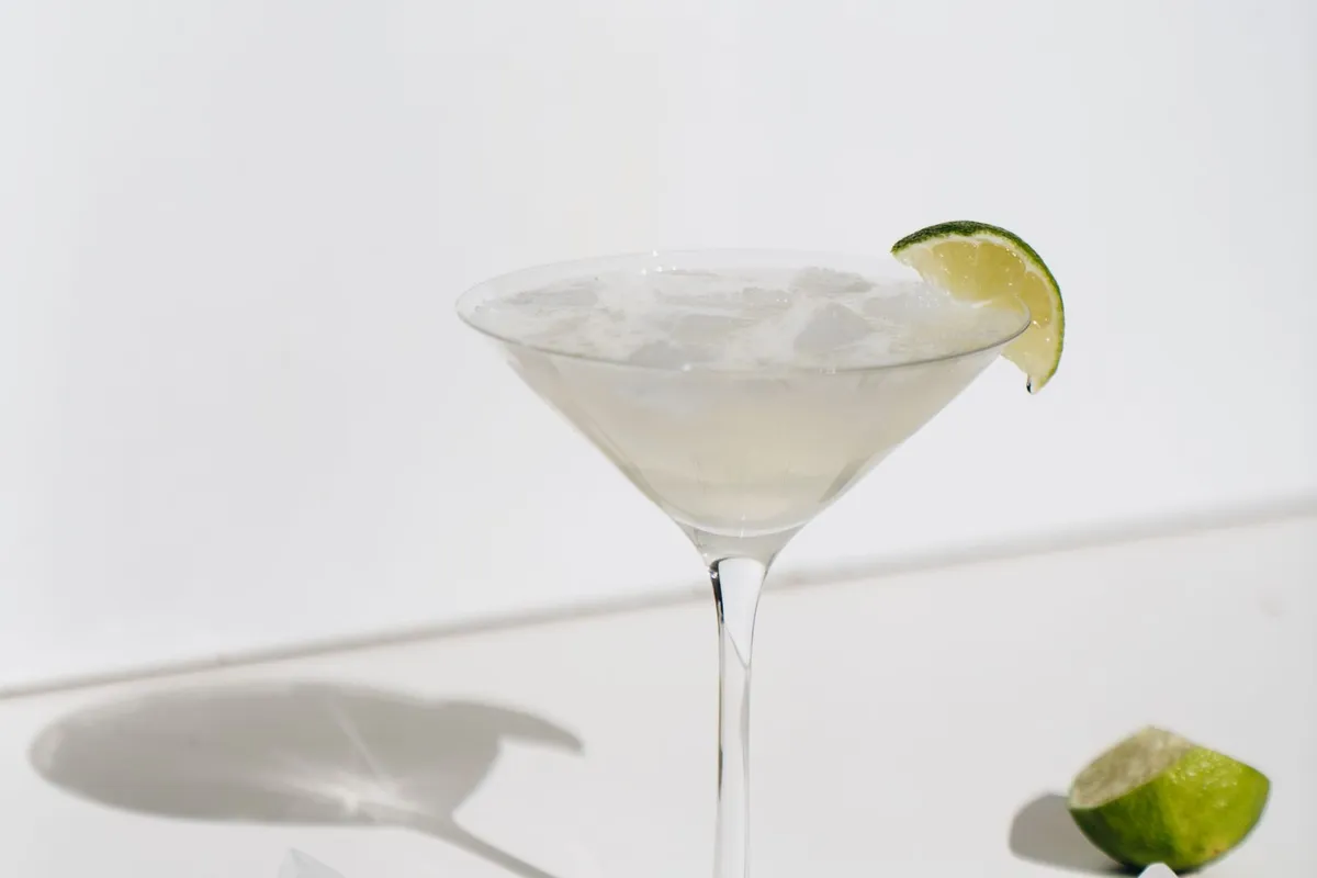 Iced margarita with a lime wedge beside scattered ice and lime pieces