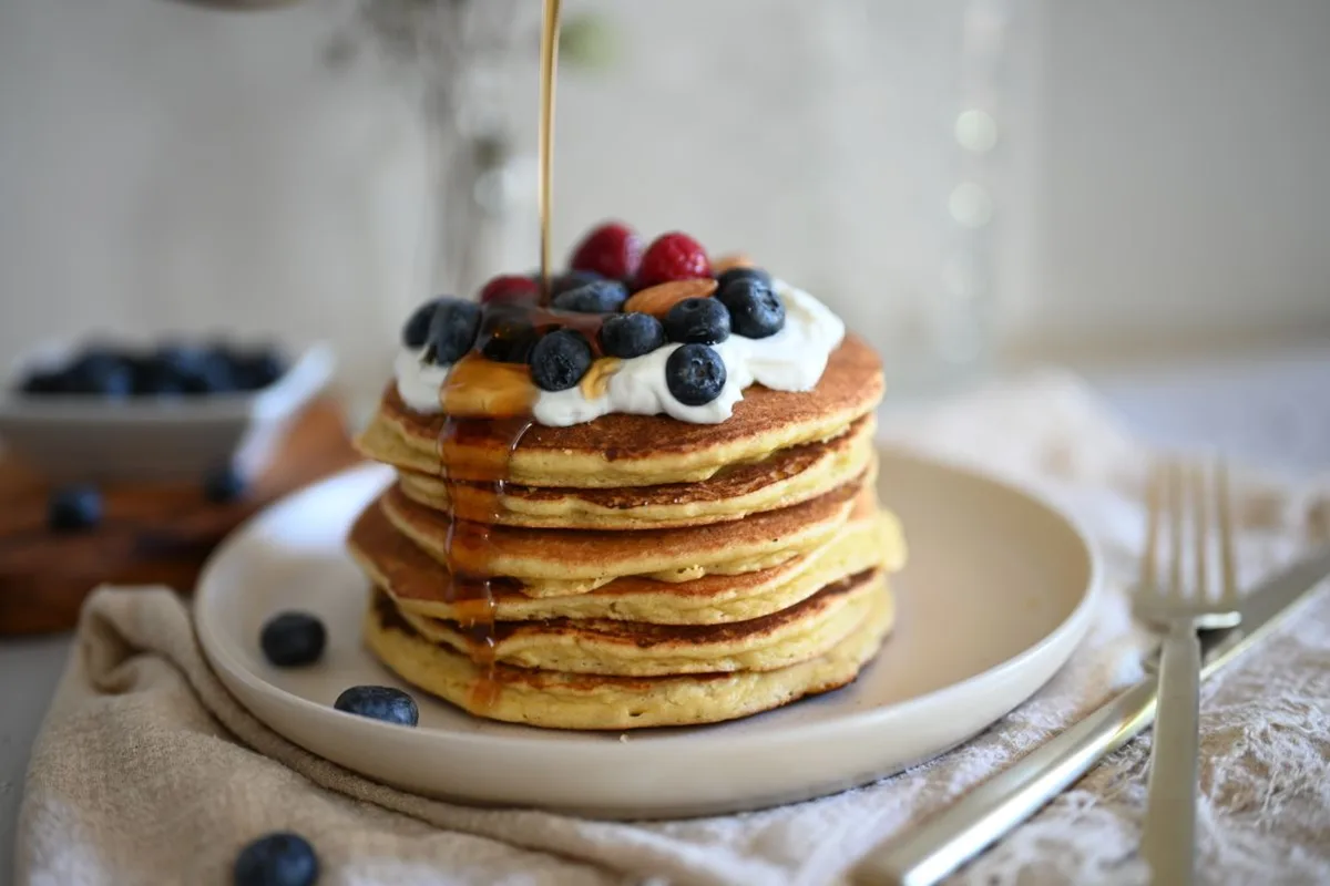 Stack of pancakes topped with blueberries, raspberries and whipped cream