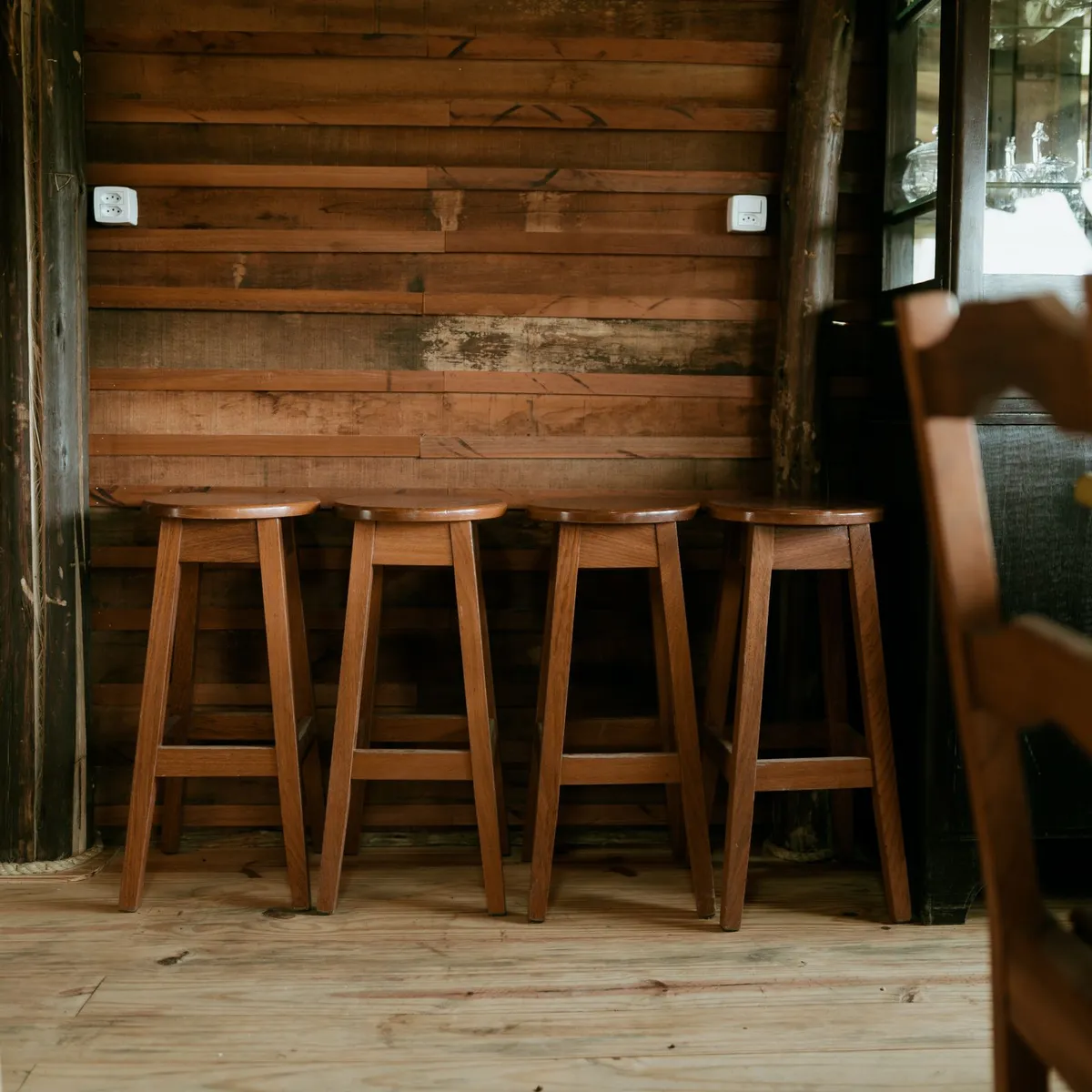 Wooden barstools lined up against a counter and wood-paneled wall